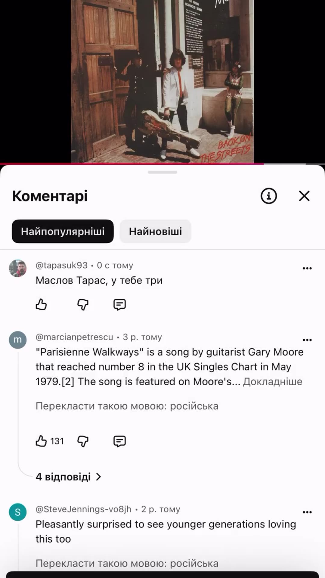 A screen recording of the YouTube app shows a comment section under a music video. The video player shows a Gary Moore album cover, and a top comment quotes facts about the song 'Parisienne Walkways'. The user types the Ukrainian comment 'Маслов Тарас, у тебе три' and posts it. It then appears at t…