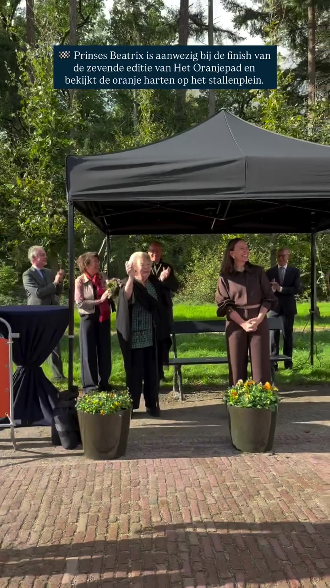 A reshared royal house video shows Princess Beatrix at the finish of the seventh Oranjepad charity walk, applauded by onlookers, viewing the orange hearts at the stable yard and riding away in a golf cart.