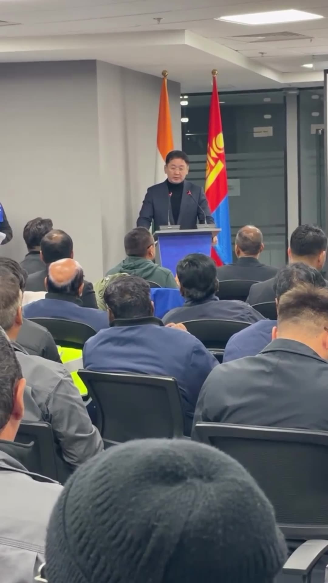 A reshared story shows a speaker addressing a seated audience in a meeting room, with Indian and Mongolian flags beside the podium and a projector screen on the side. The video is filmed from among the audience.