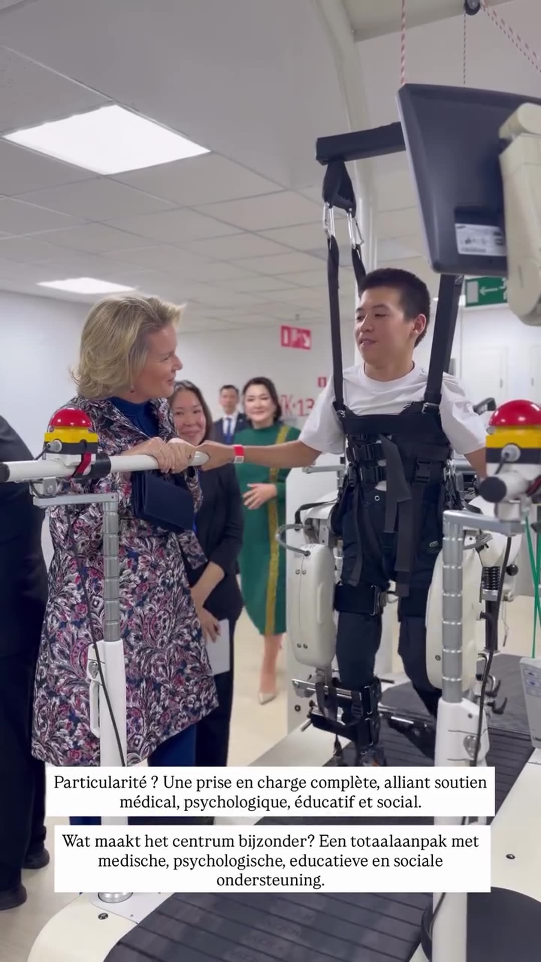 A reshared Belgian Royal Palace video shows a visit to a paediatric rehabilitation centre, where robotic gait trainers, arm therapy devices and a standing frame are demonstrated and the visitors greet children. Overlay text in French and Dutch describes the centre's comprehensive approach combining…