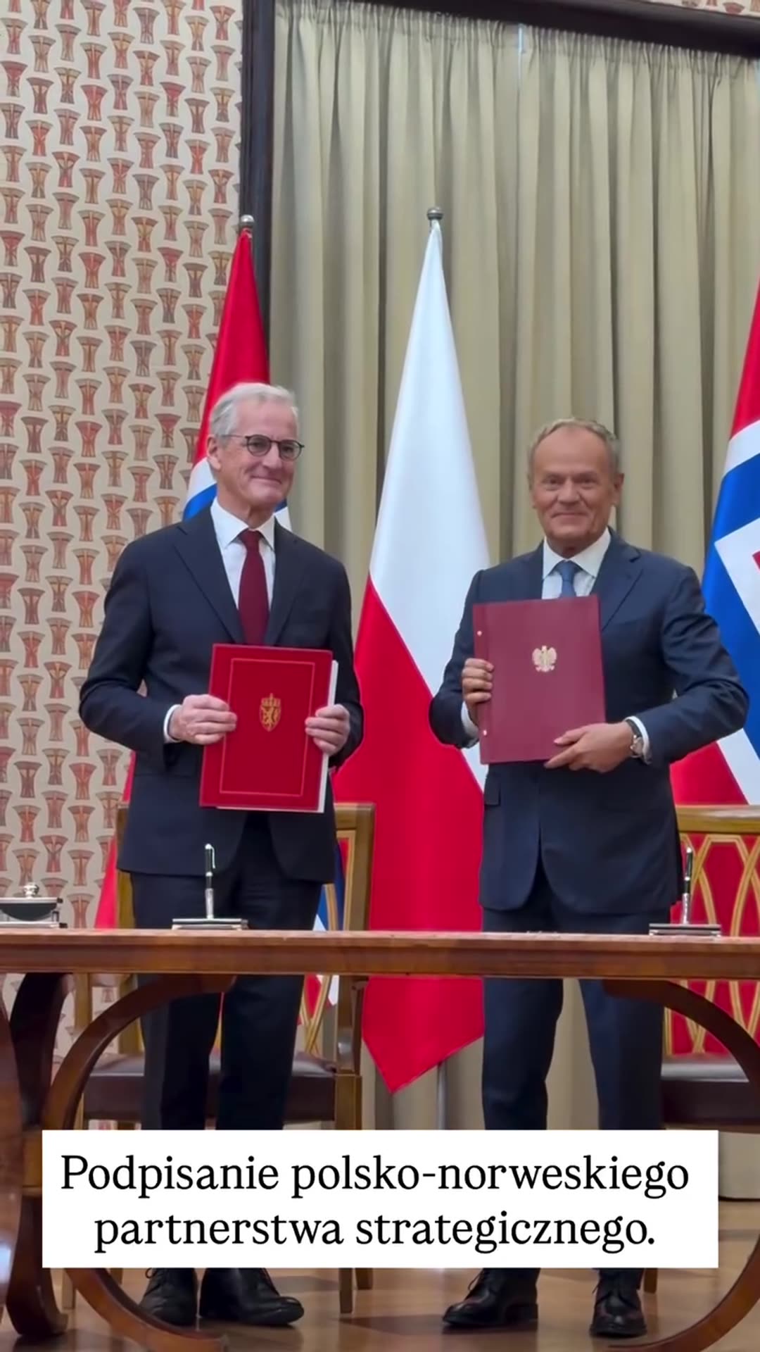 A reshared video of the signing of a Polish-Norwegian strategic partnership. The two leaders exchange red folders at a table in front of Polish and Norwegian flags, then pose with the folders.