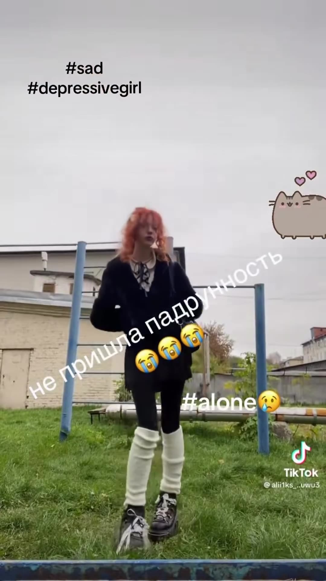 A story reposts a TikTok video from the account @alii1ks_..uwu3 showing a person with red hair in dark clothes on an outdoor bar structure in a yard, overlaid with Russian text, sad hashtags and a Pusheen cat sticker. The clip ends on a TikTok search-screen card with the author's handle.