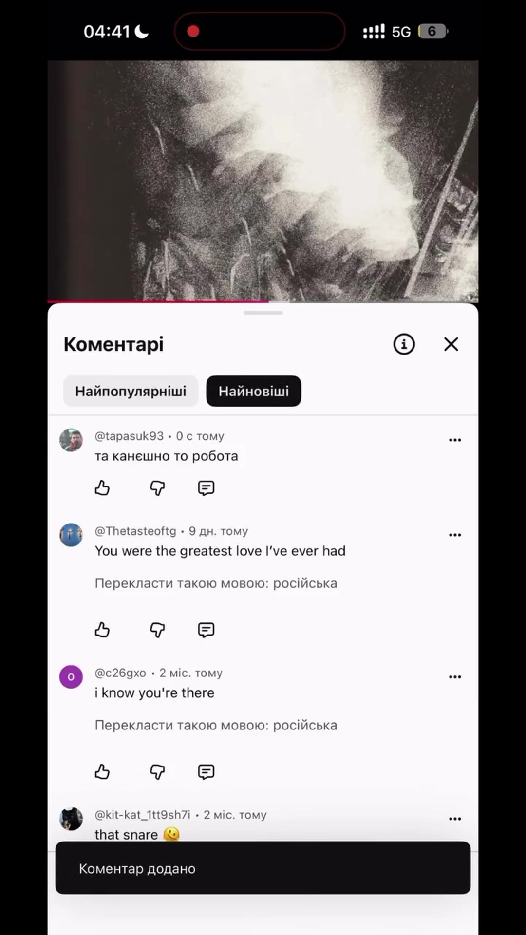 A screen recording of a phone shows a short Ukrainian comment being typed and posted in the comments of a video with a grainy black-and-white image.