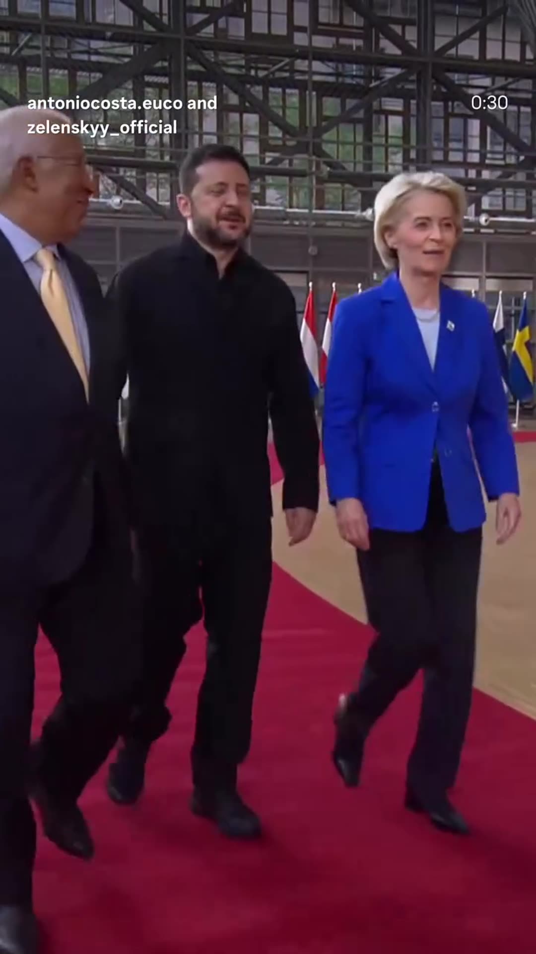 A story reshares a behind-the-scenes video from António Costa's account, tagged with Zelensky's. It shows a walk on a red carpet, a corridor greeting, a small table meeting, and a hug in the European Council hall. Photographers crowd around the leaders, and the clip ends with a camera monitor.