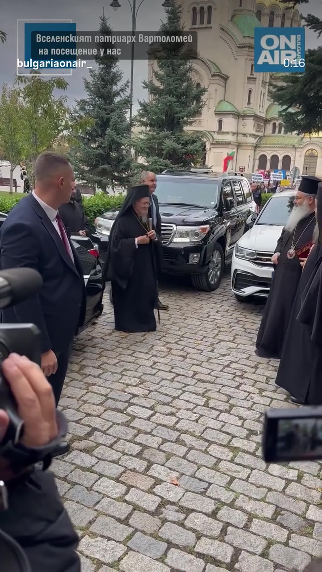 A story reshares a Bulgaria ON AIR reel showing the arrival of Ecumenical Patriarch Bartholomew in Sofia for the celebrations of St. John of Rila. Clergy greet him outside a cathedral while cameras film.