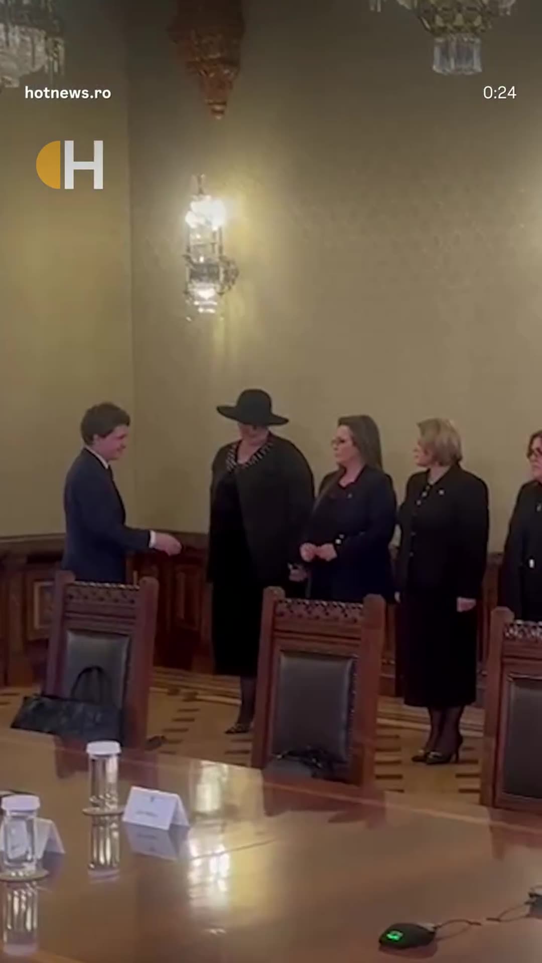 A story reshares a HotNews reel showing a man in a navy suit shaking hands with a group of people in dark clothes in an ornate meeting room. The original caption refers to an exchange of remarks between Diana Șoșoacă and Nicușor Dan, including a line that women are far superior to men.