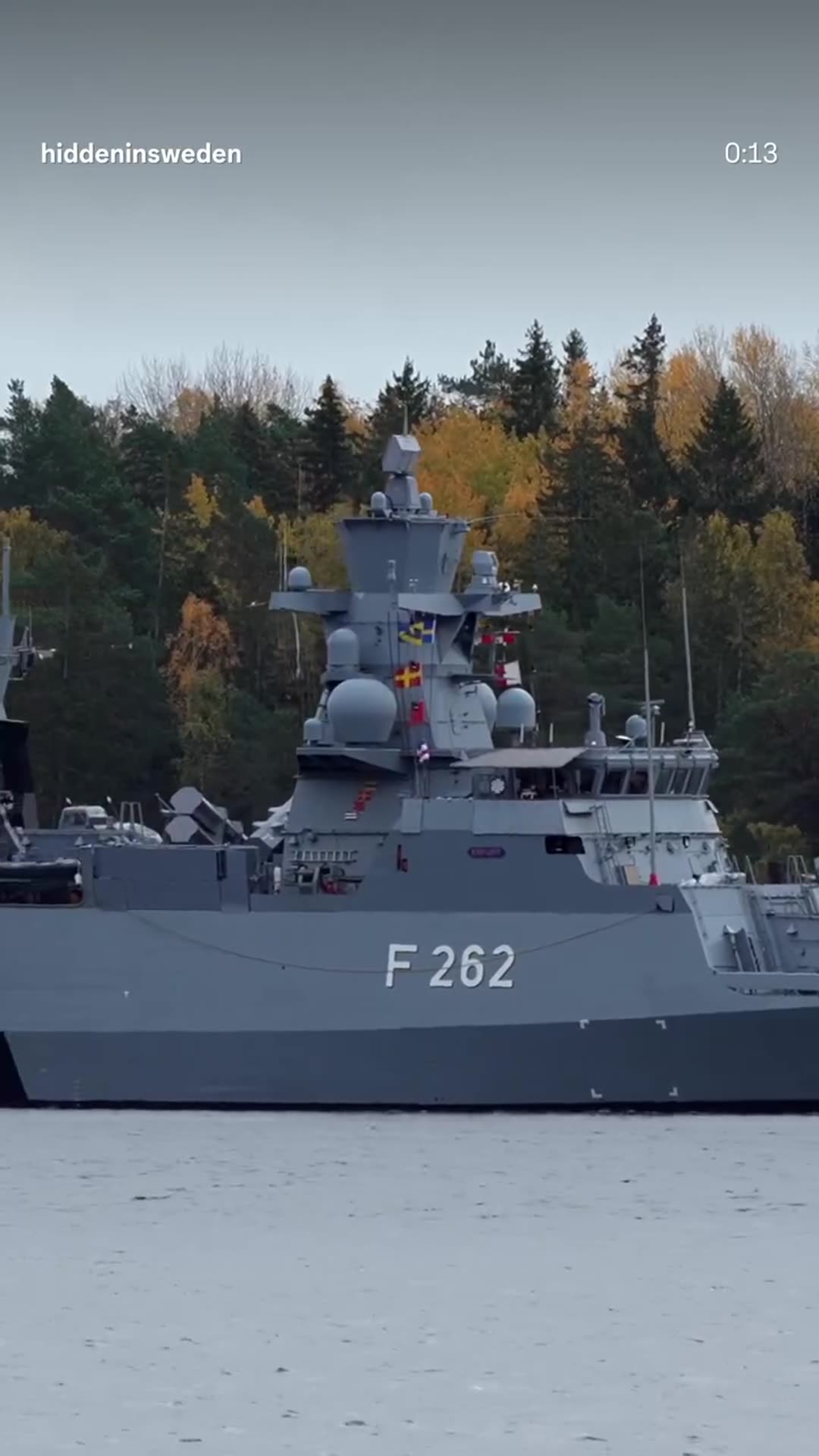 A story reshares a Hidden in Sweden reel showing the German Navy corvette F262 Erfurt passing close to rocky islets in the Stockholm archipelago, with seagulls flying past and Swedish and German flags visible on the ship.