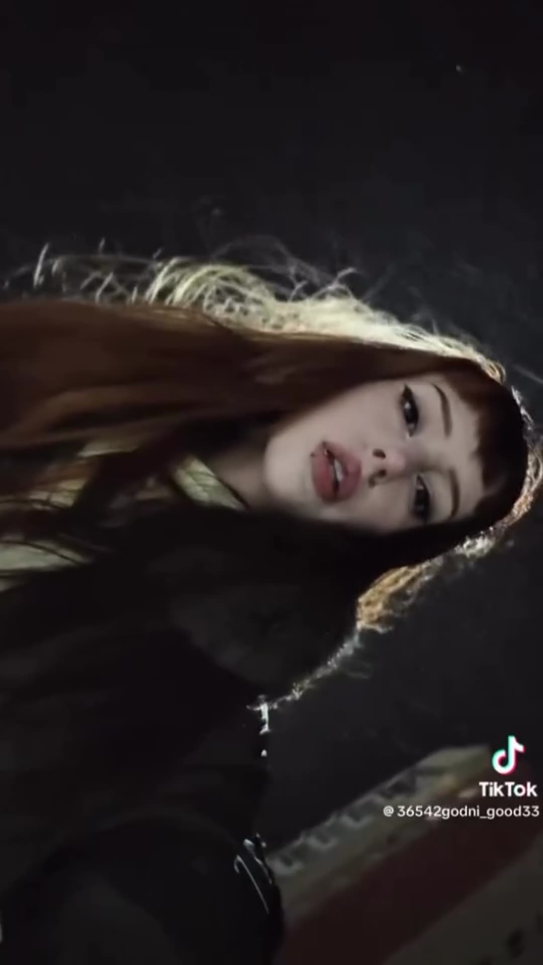 A story reshares a TikTok selfie-style video of a young woman with long auburn hair filmed outdoors at night, with a TikTok watermark and an end card showing the author's handle in a search bar.