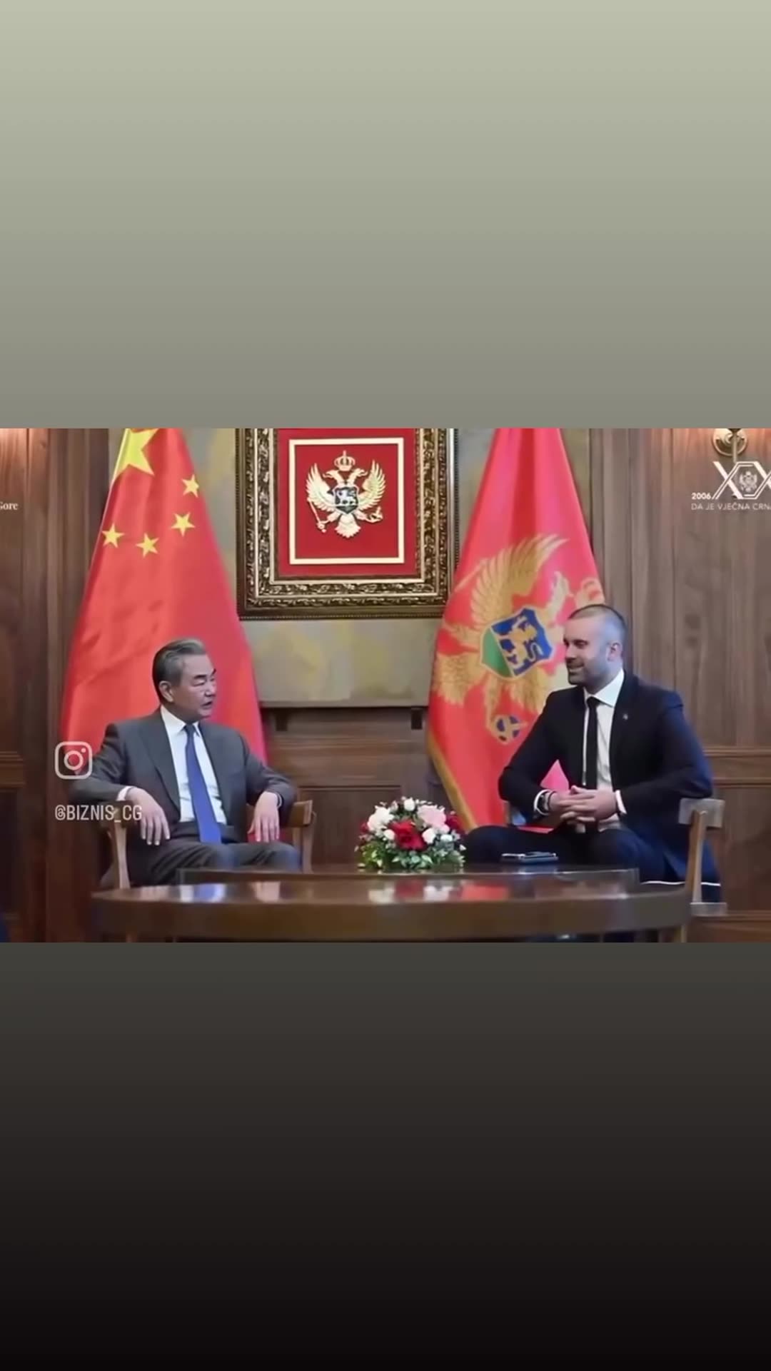 A story reshares a @biznis_cg video of a diplomatic meeting between a Chinese delegation and Montenegrin officials. It opens with a handshake at the door, then shows talks across a round table in front of the Chinese and Montenegrin flags. Yellow subtitles in Montenegrin are shown over the clips.