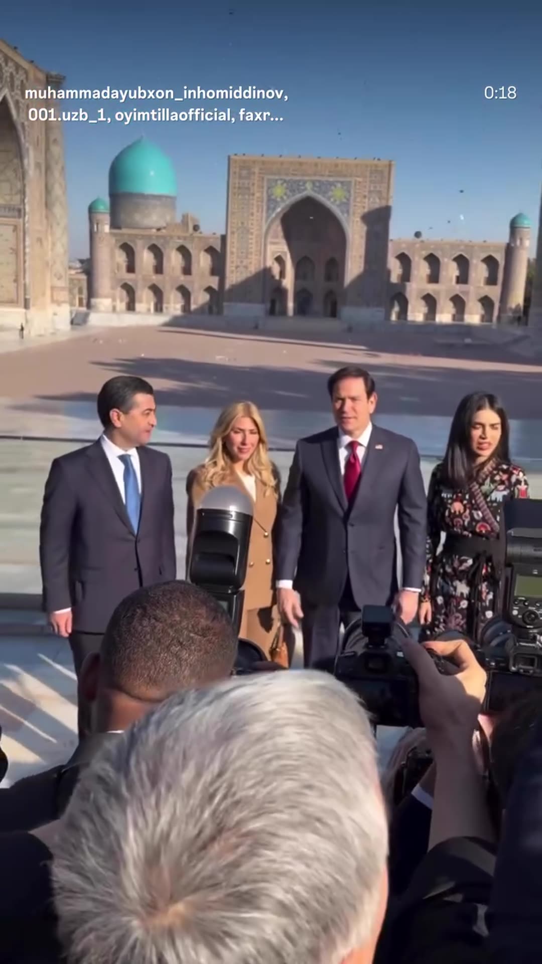 A story reshares a reel from @muhammadayubxon_inhomiddinov showing a group photo session at the Registan in Samarkand, with a US delegation and Uzbek hosts posing in front of a crowd of press photographers.