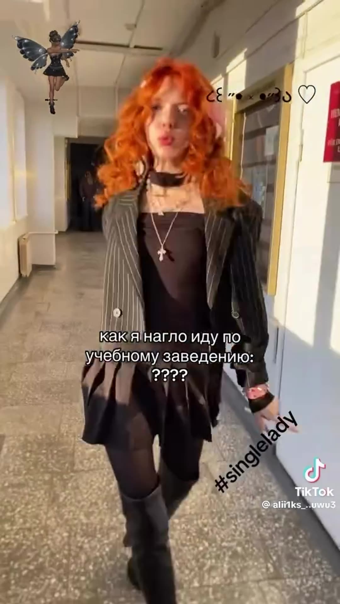 A story reshares a TikTok video by @alii1ks_..uwu3 in which a young woman with bright orange curly hair struts and dances down a sunlit school corridor, with a Russian caption joking about how boldly she walks through her educational institution, set to a song about being single. The clip ends on t…