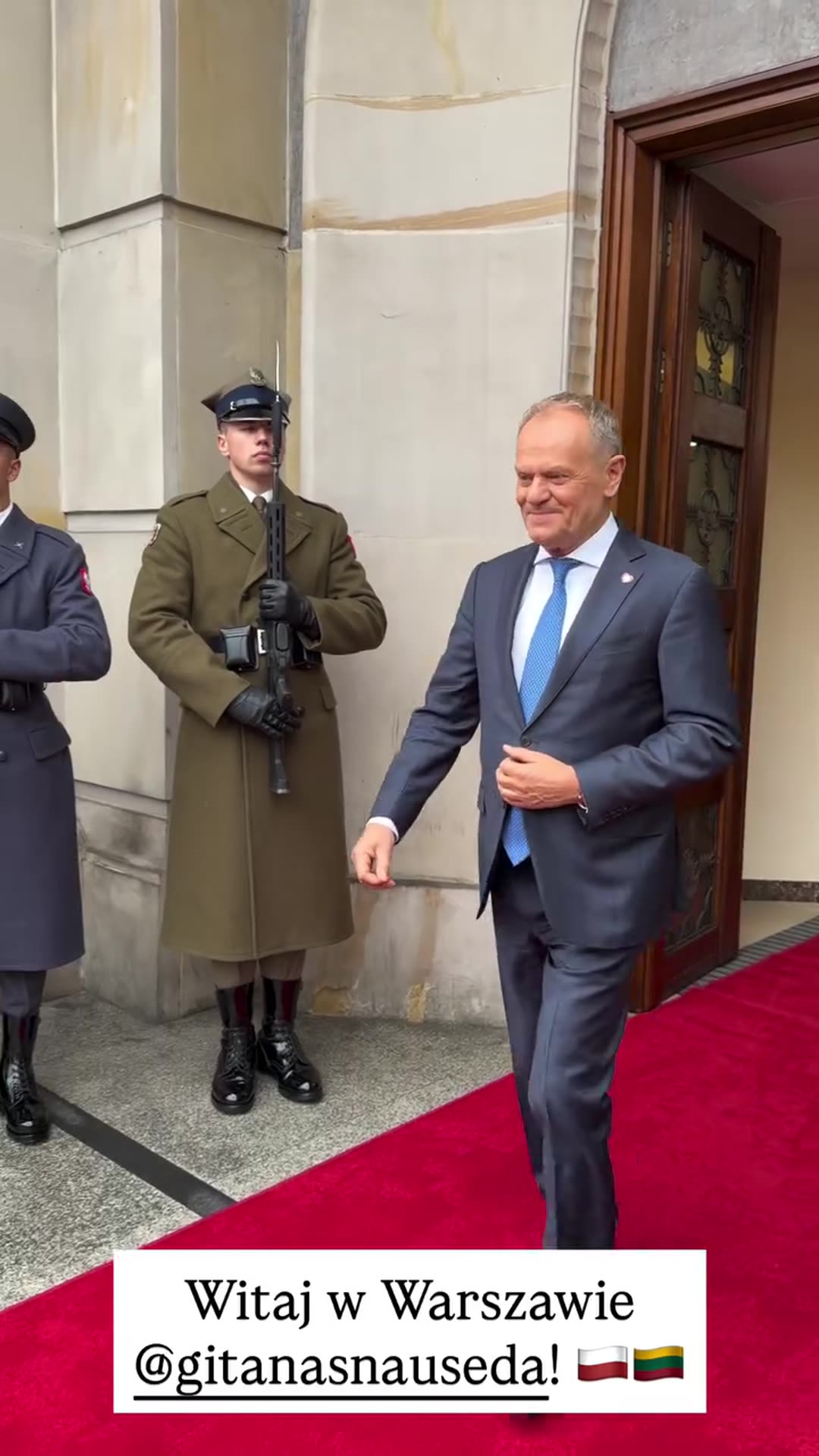 A story reshares Donald Tusk's video of his welcome of Lithuanian guest @gitanasnauseda in Warsaw: he walks out past honor guards onto a red carpet and embraces the arriving guest beside a car with a Lithuanian flag.