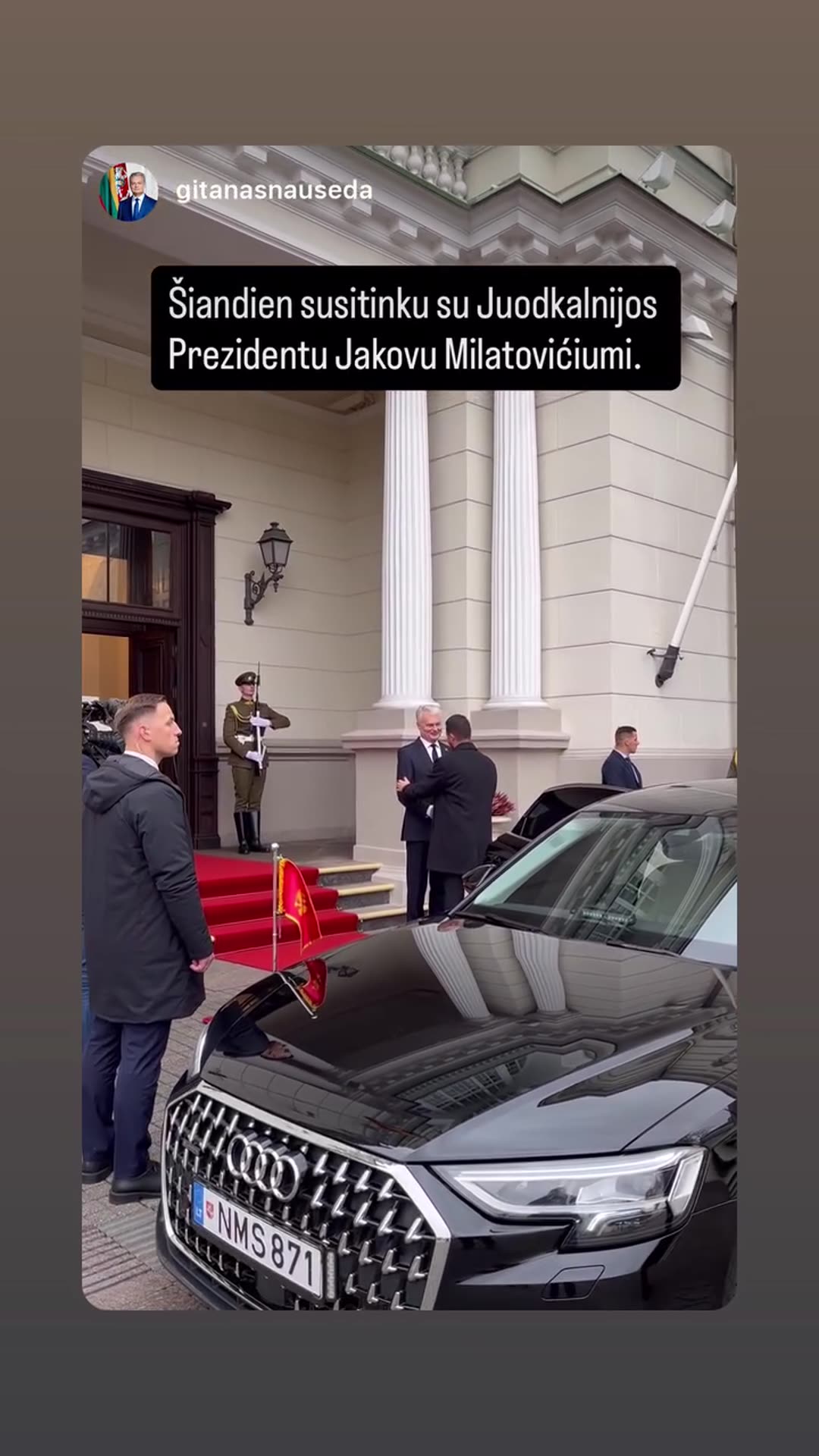 A reshared story shows the official welcome of a visiting head of state at the entrance of a palace. A black Audi with a small red flag has pulled up beside a red carpet, and the two men greet each other. On-screen Lithuanian text says that today the author is meeting the President of Montenegro, J…