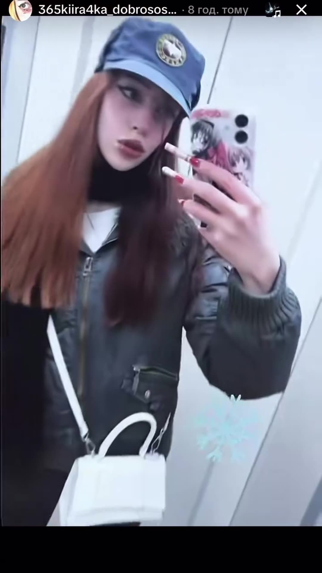 A story reshares someone else's elevator mirror-selfie video. The woman poses in a cap and jacket, holding up her phone and gesturing, with a snowflake sticker overlaid and an eye graphic near the end.