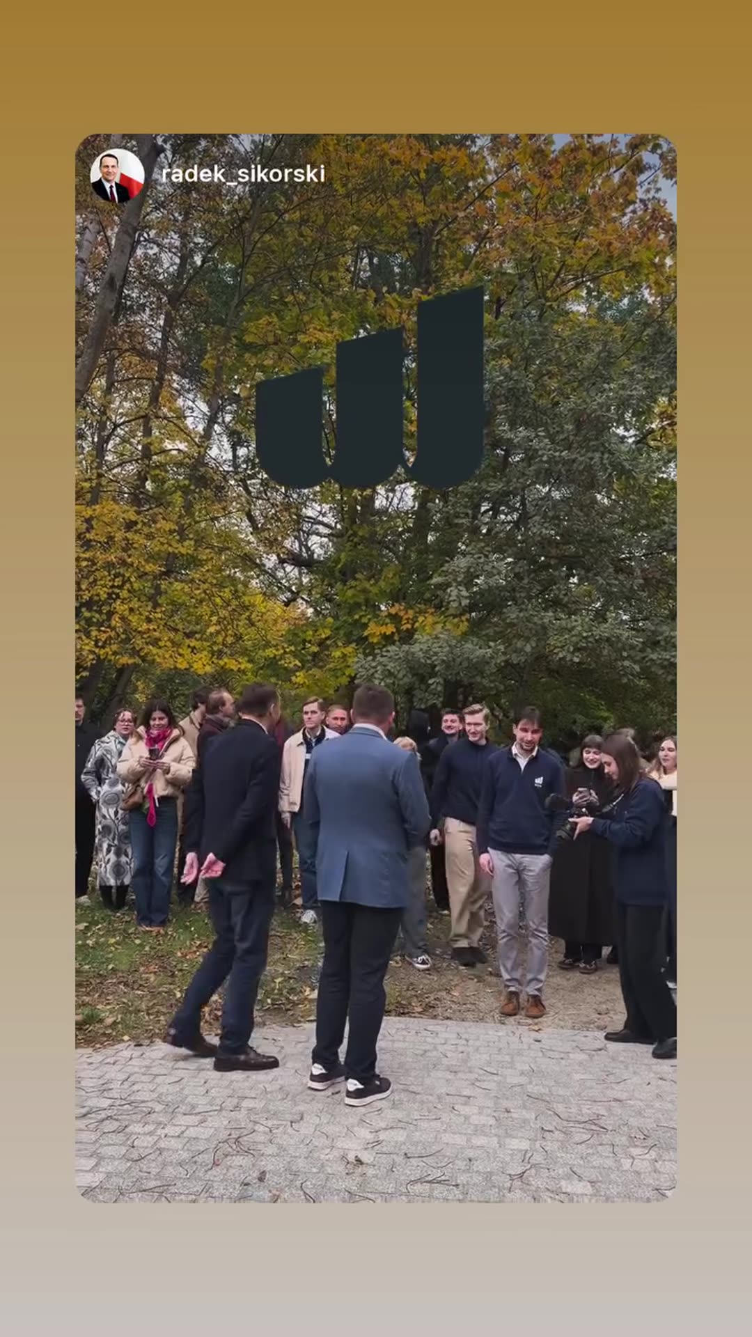 A story reshares a short video from Radosław Sikorski's account showing a group of people gathered in an autumn park, with a man in a blazer walking in front of them before the group moves forward.