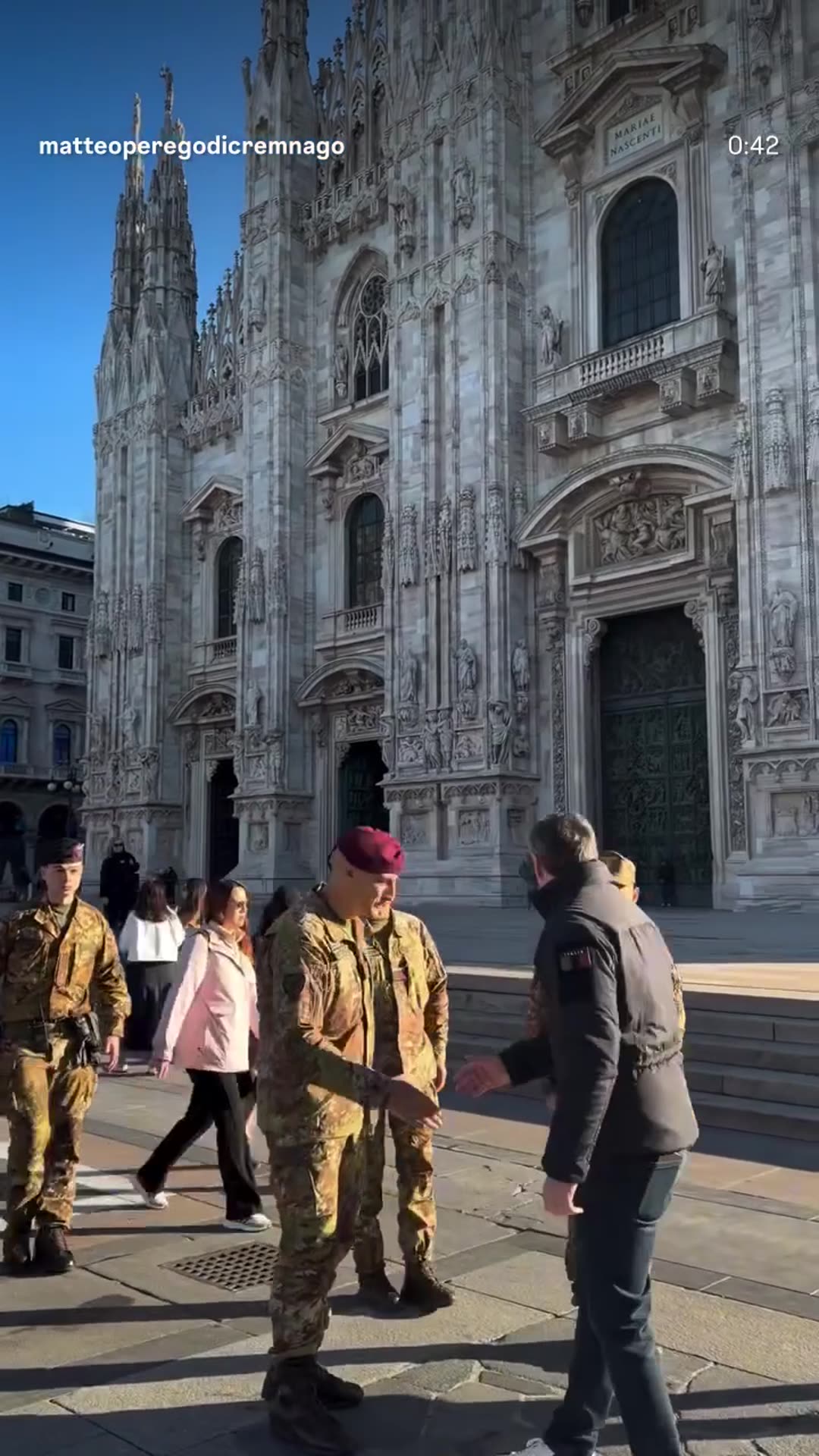 A story reshares a reel by Matteo Perego di Cremnago, captioned "Lo Stato c'è" ("The State is here"), in which he walks around central Milan greeting Italian soldiers and carabinieri deployed near the Duomo and the Galleria Vittorio Emanuele II. Armored vehicles are parked in the square.