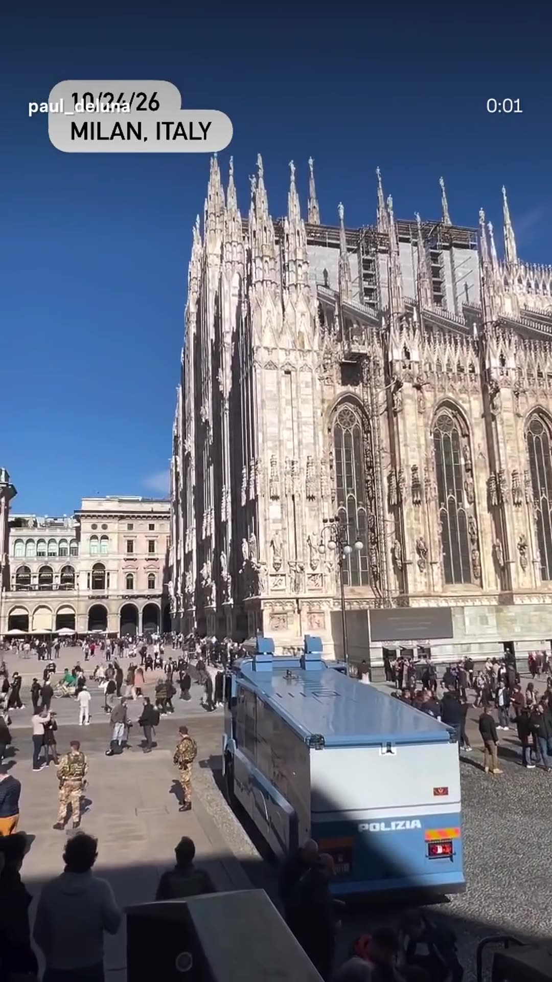 A story resharing a reel by @paul_deluna that shows Italian soldiers in maroon berets and camouflaged armored vehicles gathered on the square in front of Milan Cathedral, with a Polizia water-cannon truck nearby and crowds of people.