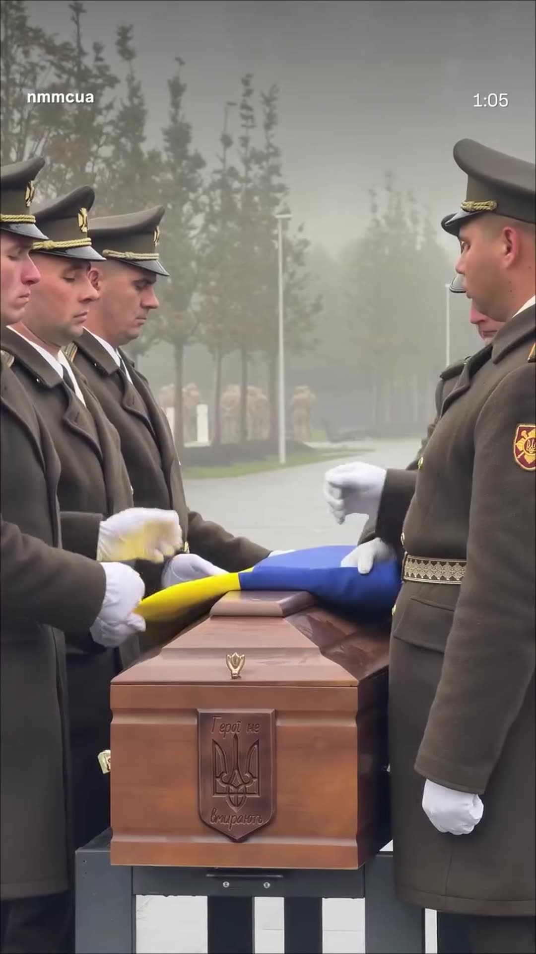 A story reshares a reel from the National Military Memorial Cemetery showing a funeral with military honors. Honor guards carry coffins from a van, a chaplain prays, a Ukrainian flag is folded, a salute is fired and coffins are carried to the graves in fog and rain.