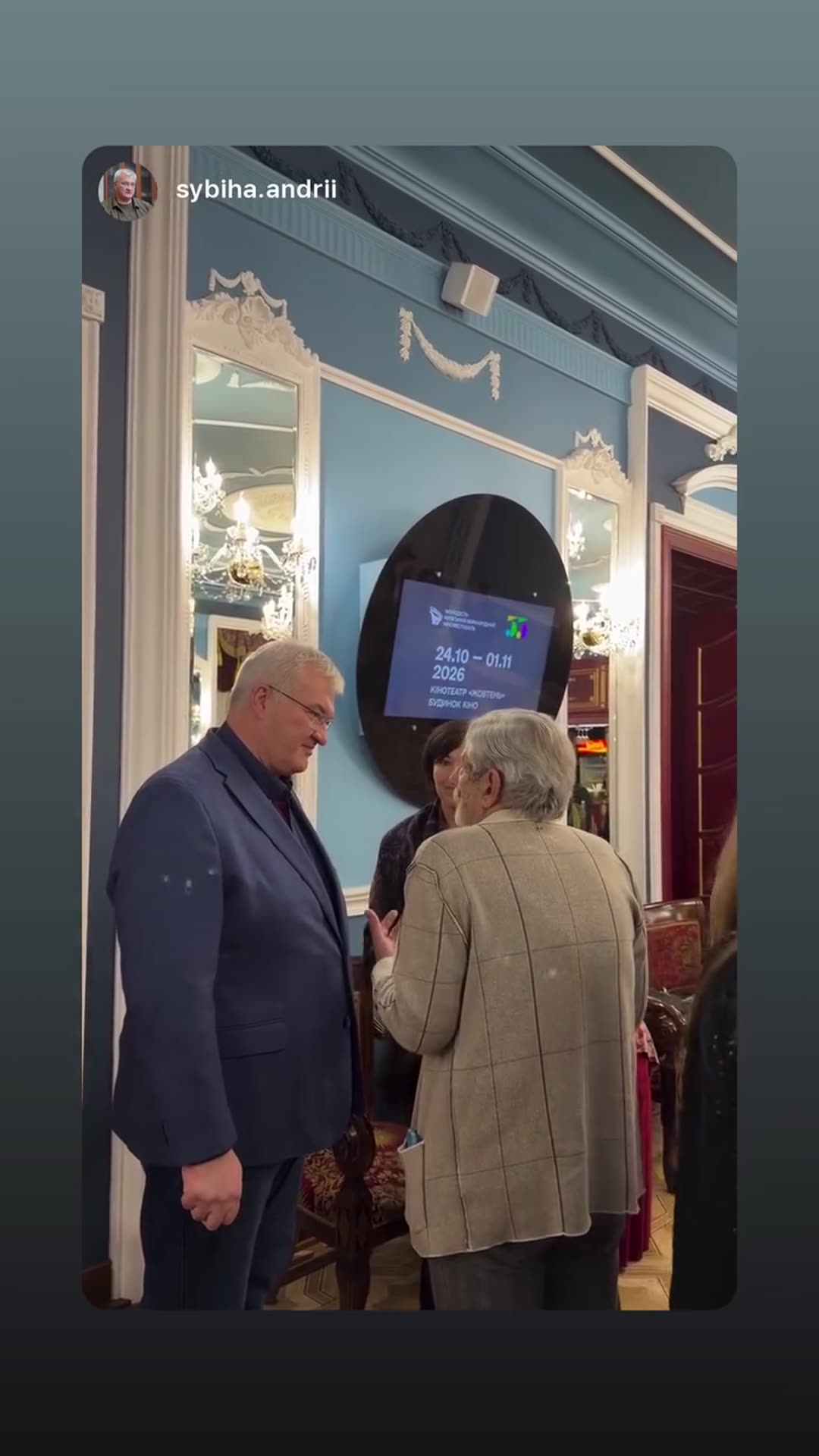 A story reshared from @sybiha.andrii showing a few people chatting in an ornate blue foyer, with a wall screen behind them cycling through festival information.