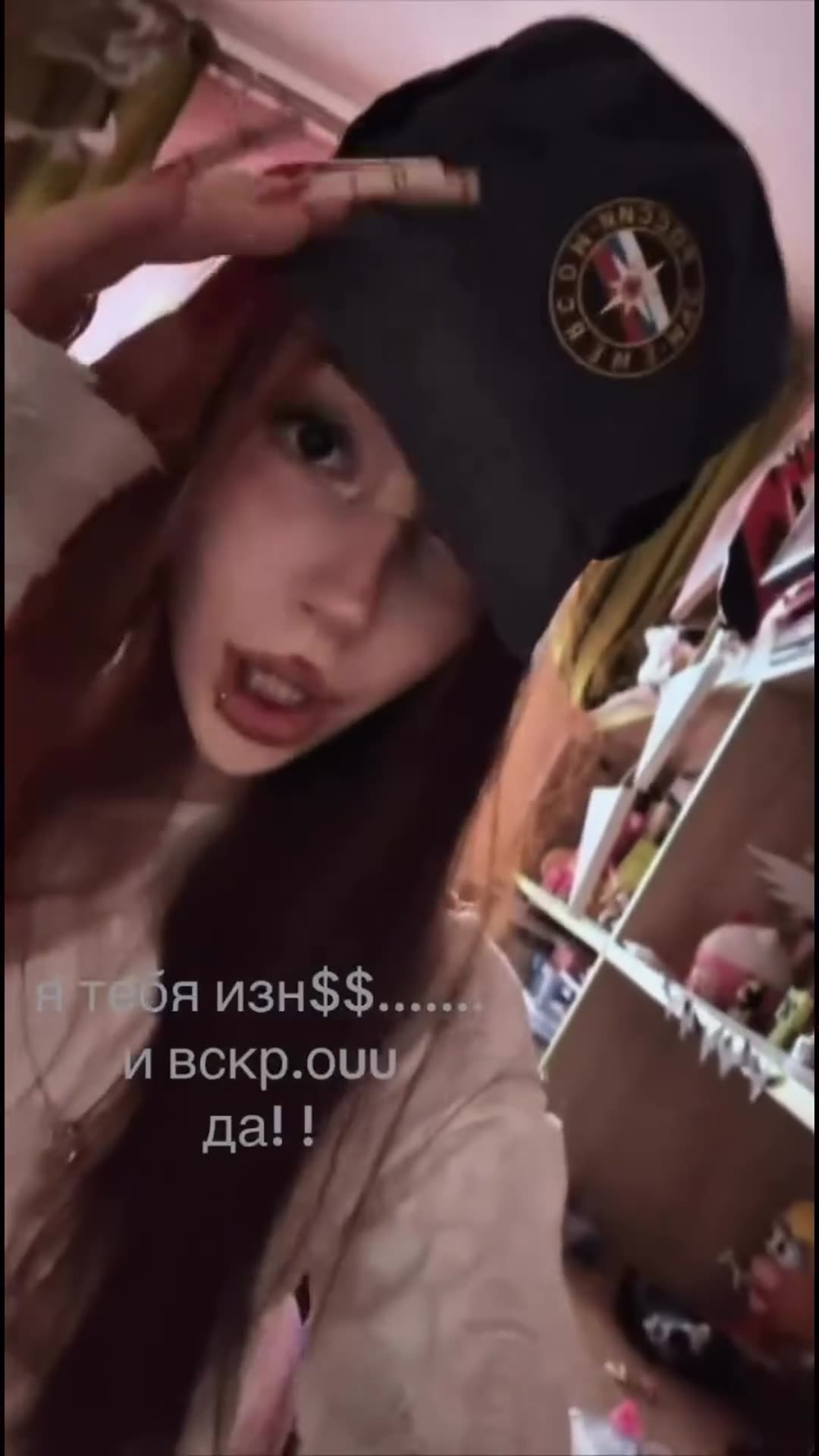 A selfie-style story of a young woman lip-syncing to a Russian audio track with violent lyrics. She wears a dark cap and holds a cigarette in a cluttered room, with Russian on-screen text echoing the lyrics.