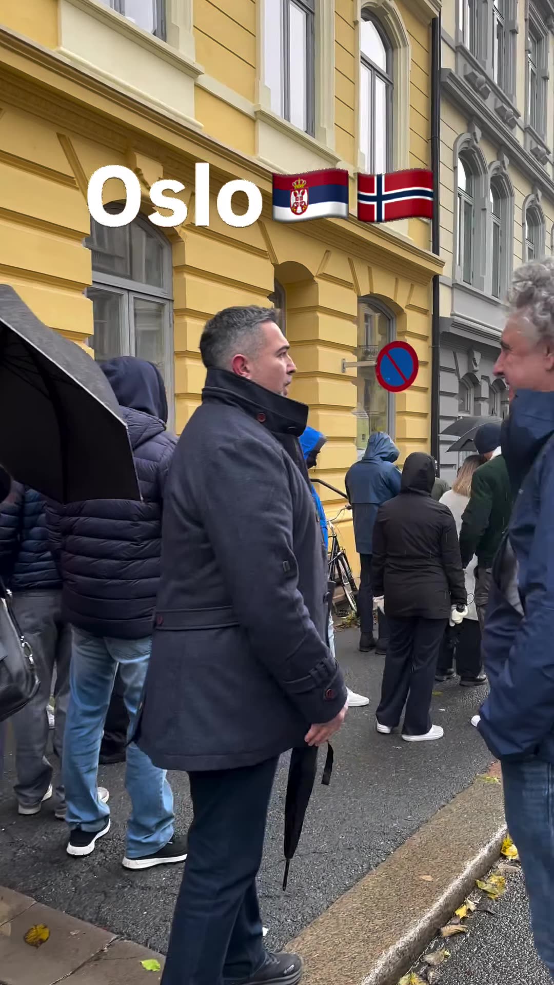 A repost of a reel filmed along the long queue of Serbian citizens waiting in the rain outside the Serbian Embassy in Oslo to vote. The narrator says people waited about three to four hours, that pregnant women and women with children were let in first, and that the queue continued inside the build…