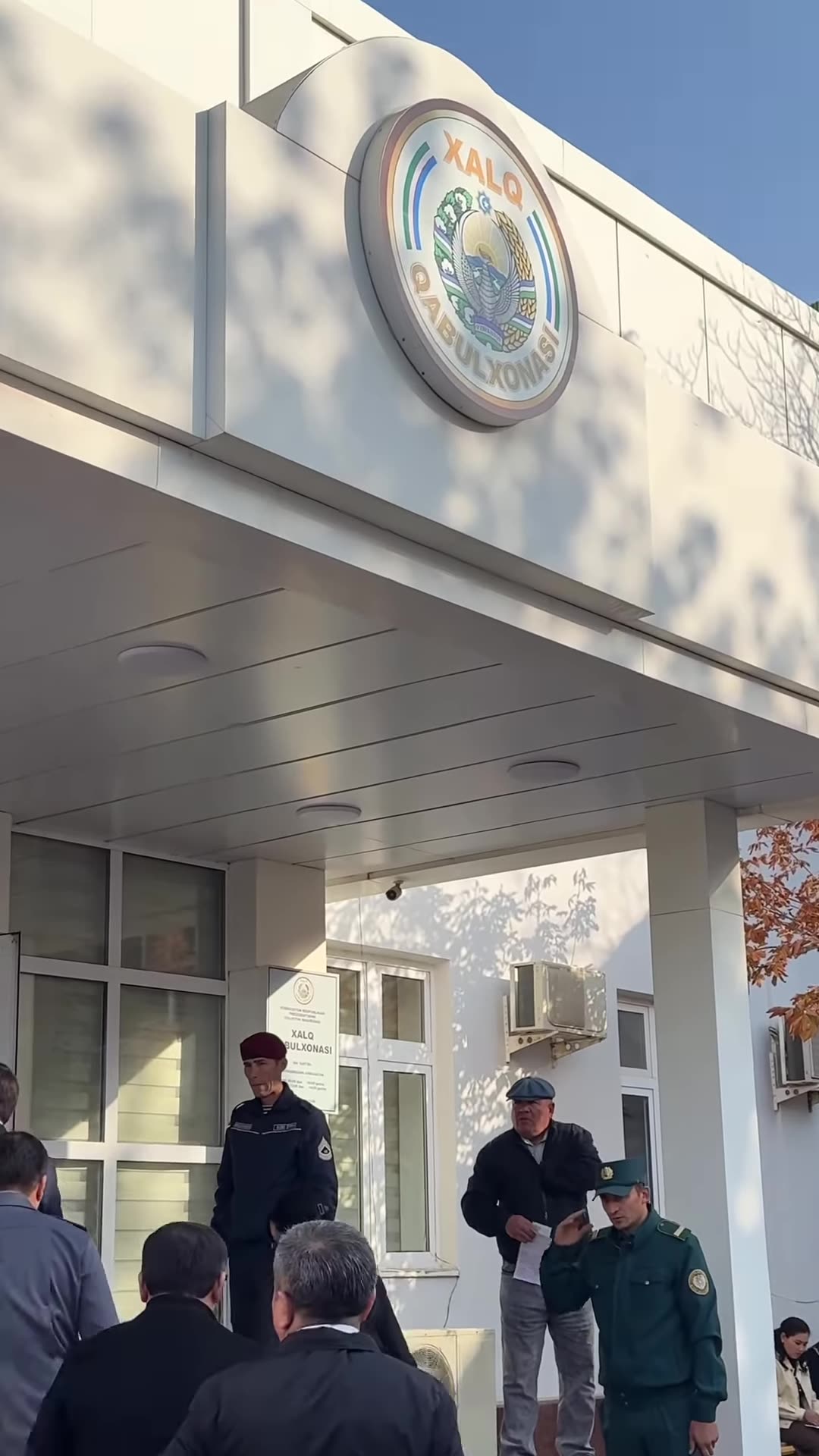 A repost of a reel showing officials walking into the People's Reception Office in Guliston, Sirdaryo region, where the acting regional governor is receiving citizens in person. Citizens and guards wait at the entrance.